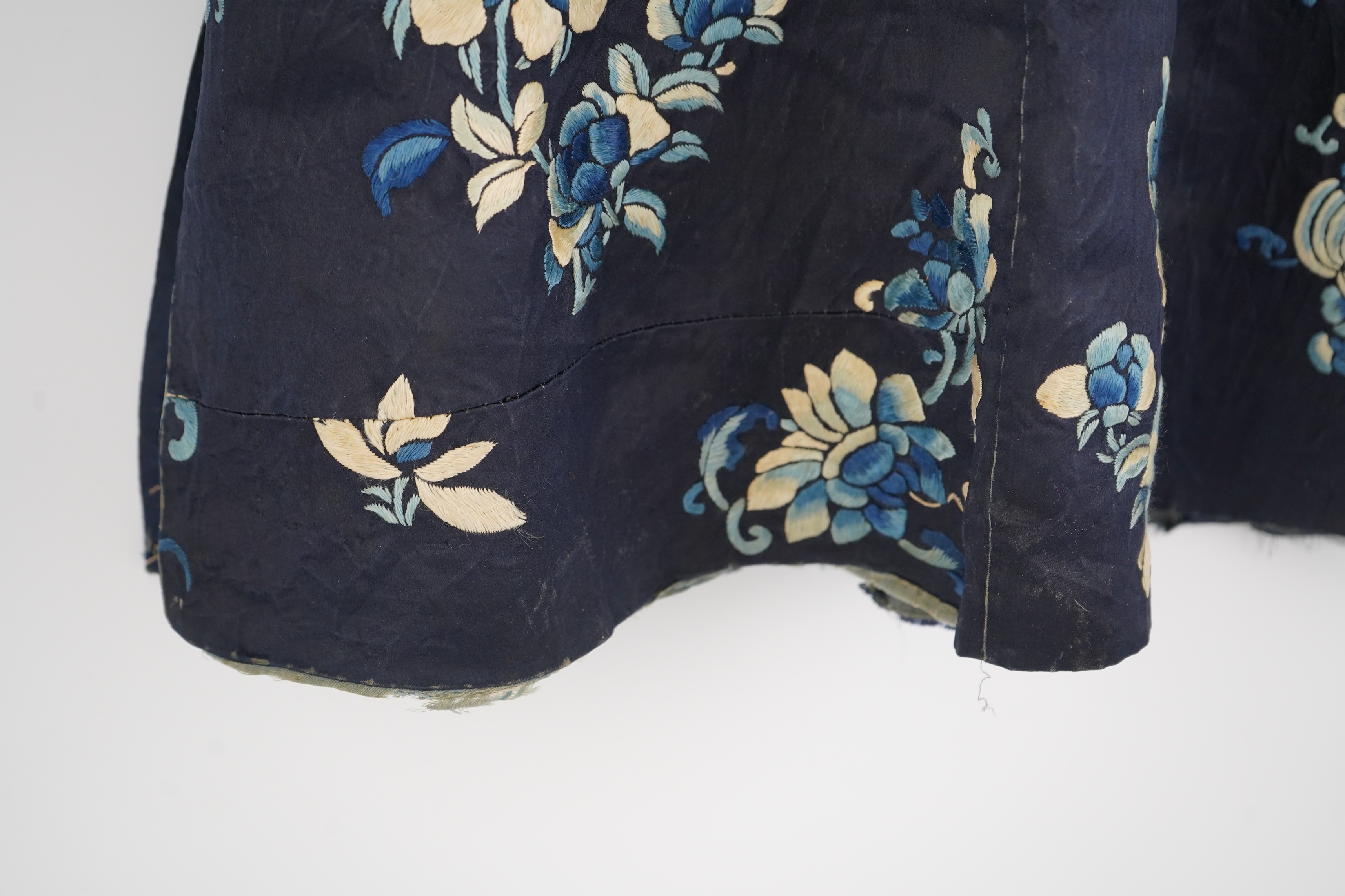 An early 20th century blue silk embroidered Chinese child’s robe, embroidered with bats and flower motifs, bordered with rows of silk braid. Condition - the original silk lining has been removed, it may benefit from bein